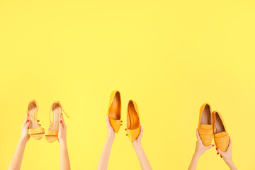 Female hands holding different shoes on yellow background
