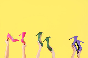 Female hands holding different shoes on yellow background