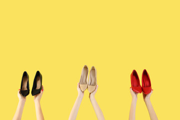 Female hands holding different shoes on yellow background
