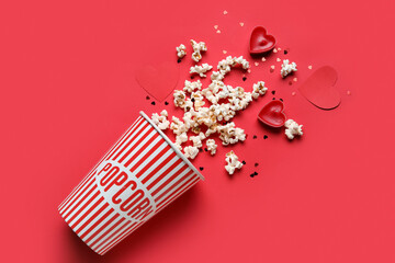 Bucket of popcorn with candles and hearts decor on red background. Valentine's Day celebration - obrazy, fototapety, plakaty