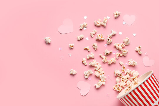 Bucket of popcorn with hearts decor on pink background. Valentine's Day celebration