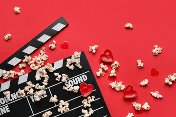Movie clapper with popcorn and candles on red background. Valentine's Day celebration