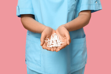Female dentist with floss toothpicks on pink background