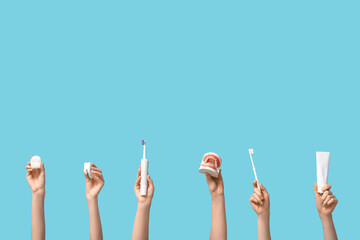 Female hands with dental models and oral hygiene supplies on blue background