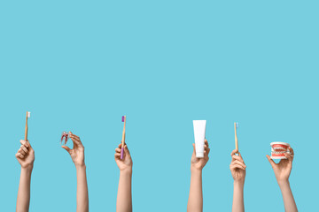 Female hands with dental models and oral hygiene supplies on blue background - obrazy, fototapety, plakaty