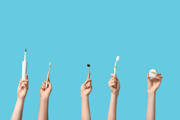 Female hands with toothbrushes, dental floss and mirror on blue background