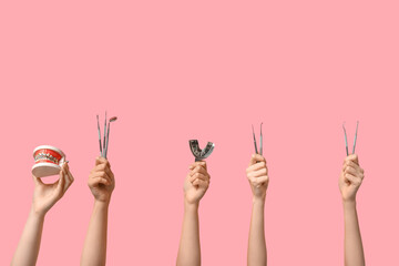 Female hands with dental tools and jaw model on pink background - obrazy, fototapety, plakaty