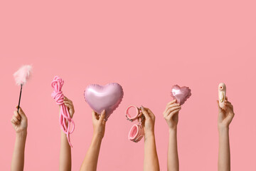 Many female hands with heart shaped balloons and sex toys on pink background. Valentine's Day...