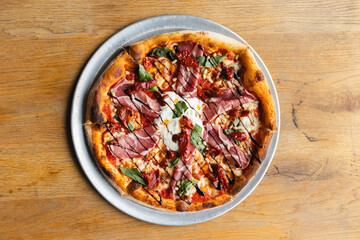 Appetizing pizza with tomato sauce, meat, basil and cheese.