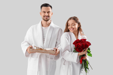 Young couple with tasty breakfast and roses on light background. Valentine's Day celebration