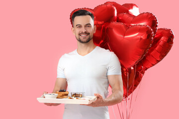 Young man with tasty breakfast and heart-shaped balloons on pink background. Valentine's Day...