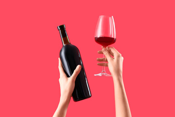 Woman with bottle and glass of wine on red background. Valentine's Day celebration