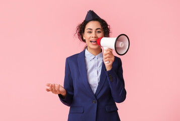 Beautiful African-American stewardess with megaphone on pink background