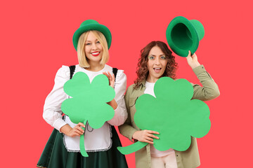 Portrait of women with paper clover celebrating St. Patrick's Day on red background