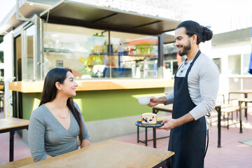 Latin worker taking the order of a happy customer at the coffee shop