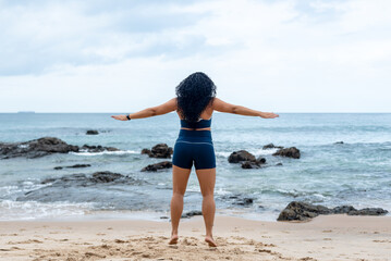 Fototapeta na wymiar Fitness woman, athlete, doing jumping jacks on the beach sand.
