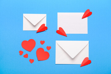 Envelopes with blank card and red paper hearts on blue background. Valentine's Day celebration