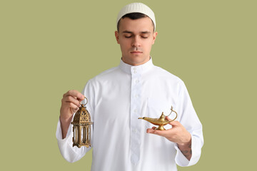 Young Muslim man with lamps on green background. Ramadan celebration