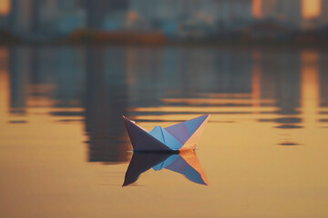 Leadership concept. Paper boat sailing on water with sunset time.