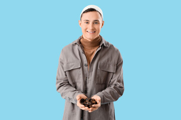 Young Muslim man with dates on blue background. Ramadan celebration