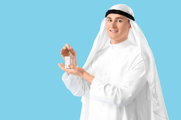 Young Muslim man with lamp on blue background. Ramadan celebration
