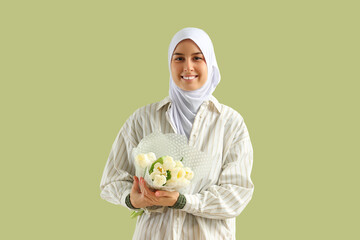 Young Muslim woman with tulips on green background. Ramadan celebration