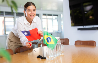 Employee of delegation prepares negotiating table - sets up the flag of Brazil and Taiwan