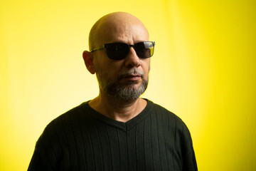 White man, bald, wearing sunglasses, smiling looking at the camera.