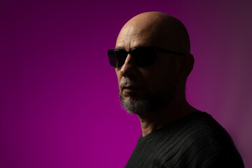 Handsome, bald and bearded man in sunglasses looking towards the camera.