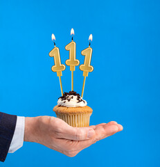Hand delivering birthday cupcake - Candle number 111 on blue background