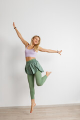 Happy athletic woman dancing in modern fitness attire, white background.