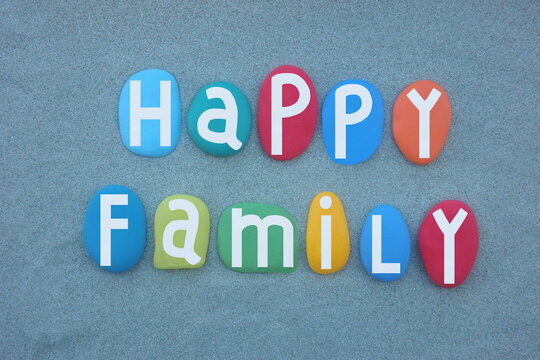 Happy Family, creative text composed with hand painted multi colored stone letters over green sand