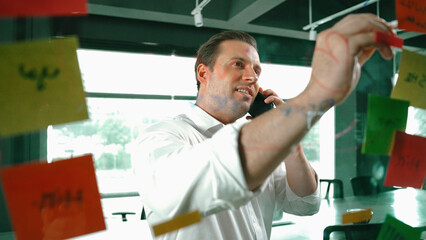 Professional businessman making phone call to customers while looking at marketing strategy idea...