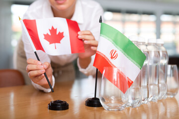 Little flag of Iran on table with bottles of water and flag of Canada put next to it by positive...