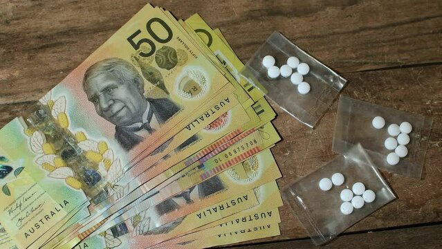 Close-up, looking down, drug deal mockup, Australian dollars fanned out, three single plastic bags of illegal party drug, tablets, enters the frame one-by-one,  rustic setting 