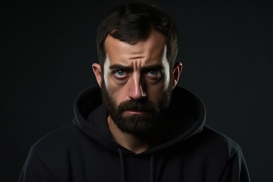 Portrait of a man in a black hoodie on a dark background