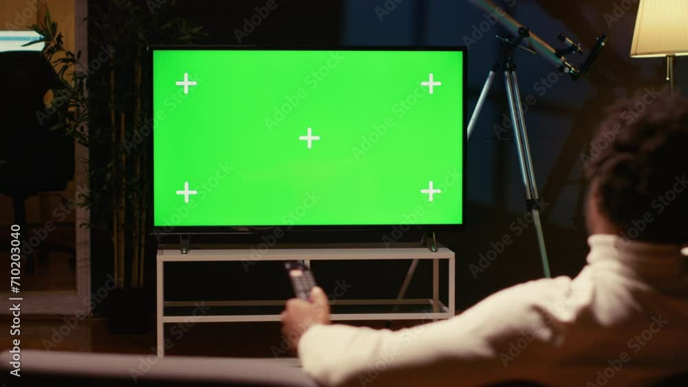 Poster man using remote to zap through films available on streaming services on mockup tv. person having mo
