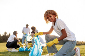 multiracial group of people volunteers with garbage bags collect garbage and plastic in the park,...