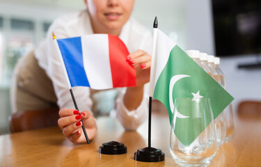 Little flag of Pakistan on table with bottles of water and flag of France put next to it by...