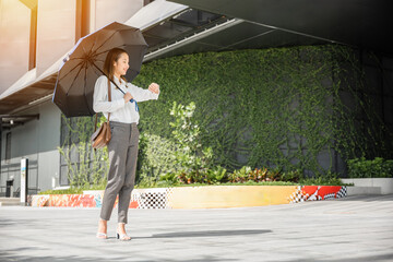 In hot weather, a young businesswoman uses an umbrella on her way to the office, checking the time...