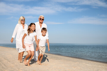 Cute little children with grandparents spending time together on sea beach