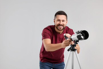 Obraz premium Smiling astronomer with telescope on light grey background. Space for text