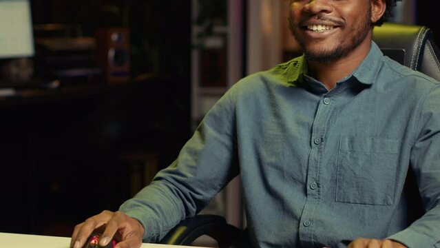 Happy african american man using gaming keyboard to play videogames at home. Gamer using powerful PC and computer peripherals to compete in online multiplayer game competition