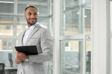 Happy man with clipboard in office, space for text. Lawyer, businessman, accountant or manager