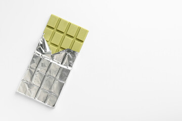 Tasty matcha chocolate bar wrapped in foil on white background, top view. Space for text