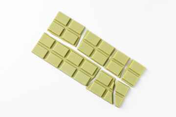 Pieces of tasty matcha chocolate bars on white background, top view