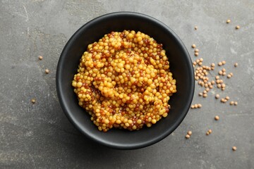 Whole grain mustard in bowl and dry seeds on grey table, flat lay