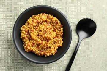 Whole grain mustard in bowl and spoon on light table, flat lay