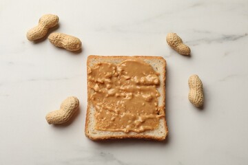 Delicious toast with peanut butter and nuts on white marble table, flat lay