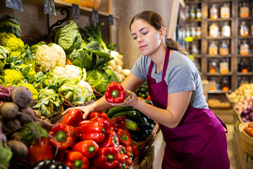 Obraz premium Saleswoman near fruit and vegetables stalls offering to buy paprika
